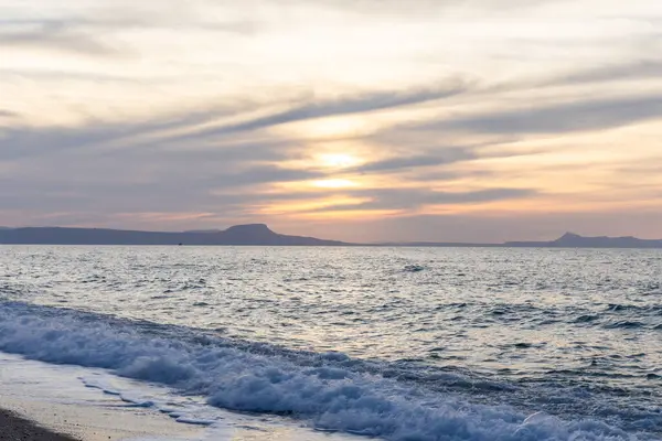 Gün batımında kumlu ve çakıl taşı plajı olan güzel bir sahil şeridi. Platanes Beach, Rethymno, Girit, Yunanistan 'ın turizm ve otel bölgesinde güzel gökyüzü renklendirmesi