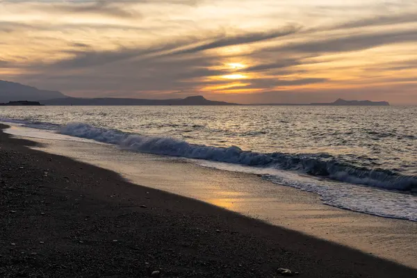 Gün batımında kumlu ve çakıl taşı plajı olan güzel bir sahil şeridi. Platanes Beach, Rethymno, Girit, Yunanistan 'ın turizm ve otel bölgesinde güzel gökyüzü renklendirmesi