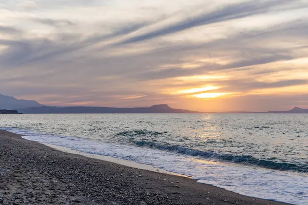 Gün batımında kumlu ve çakıl taşı plajı olan güzel bir sahil şeridi. Platanes Beach, Rethymno, Girit, Yunanistan 'ın turizm ve otel bölgesinde güzel gökyüzü renklendirmesi
