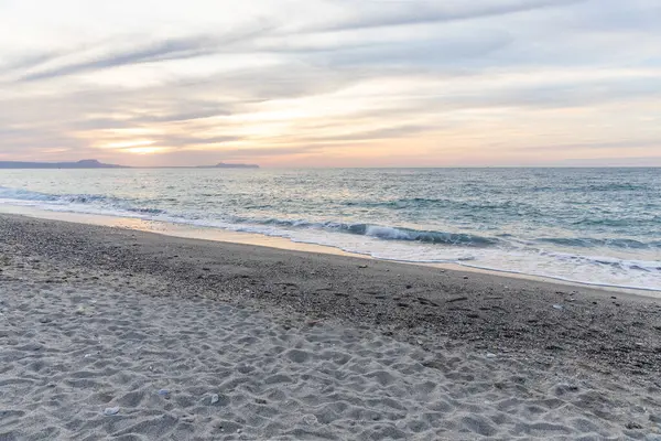 Gün batımında kumlu ve çakıl taşı plajı olan güzel bir sahil şeridi. Platanes Beach, Rethymno, Girit, Yunanistan 'ın turizm ve otel bölgesinde güzel gökyüzü renklendirmesi