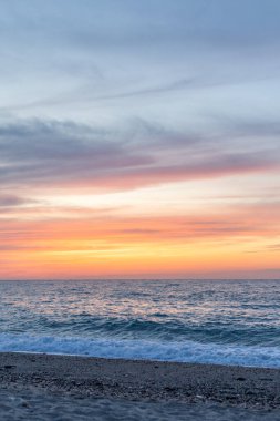 Gün batımında kumlu ve çakıl taşı plajı olan güzel bir sahil şeridi. Platanes Beach, Rethymno, Girit, Yunanistan 'ın turizm ve otel bölgesinde güzel gökyüzü renklendirmesi