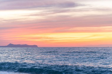 Gün batımında kumlu ve çakıl taşı plajı olan güzel bir sahil şeridi. Platanes Beach, Rethymno, Girit, Yunanistan 'ın turizm ve otel bölgesinde güzel gökyüzü renklendirmesi