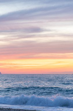 Gün batımında kumlu ve çakıl taşı plajı olan güzel bir sahil şeridi. Platanes Beach, Rethymno, Girit, Yunanistan 'ın turizm ve otel bölgesinde güzel gökyüzü renklendirmesi