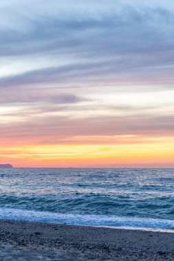 Gün batımında kumlu ve çakıl taşı plajı olan güzel bir sahil şeridi. Platanes Beach, Rethymno, Girit, Yunanistan 'ın turizm ve otel bölgesinde güzel gökyüzü renklendirmesi