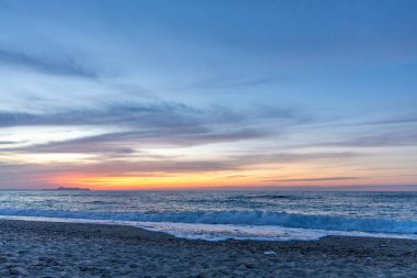 Gün batımında kumlu ve çakıl taşı plajı olan güzel bir sahil şeridi. Platanes Beach, Rethymno, Girit, Yunanistan 'ın turizm ve otel bölgesinde güzel gökyüzü renklendirmesi