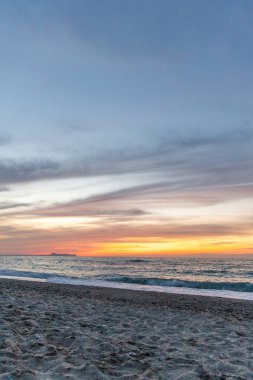 Gün batımında kumlu ve çakıl taşı plajı olan güzel bir sahil şeridi. Platanes Beach, Rethymno, Girit, Yunanistan 'ın turizm ve otel bölgesinde güzel gökyüzü renklendirmesi