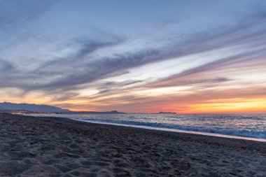 Gün batımında kumlu ve çakıl taşı plajı olan güzel bir sahil şeridi. Platanes Beach, Rethymno, Girit, Yunanistan 'ın turizm ve otel bölgesinde güzel gökyüzü renklendirmesi
