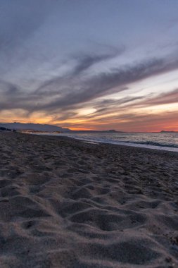 Gün batımında kumlu ve çakıl taşı plajı olan güzel bir sahil şeridi. Platanes Beach, Rethymno, Girit, Yunanistan 'ın turizm ve otel bölgesinde güzel gökyüzü renklendirmesi