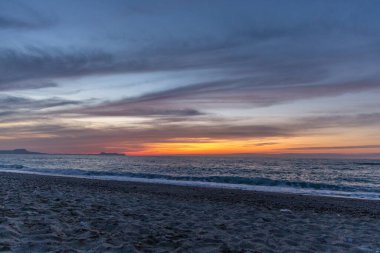 Gün batımında kumlu ve çakıl taşı plajı olan güzel bir sahil şeridi. Platanes Beach, Rethymno, Girit, Yunanistan 'ın turizm ve otel bölgesinde güzel gökyüzü renklendirmesi