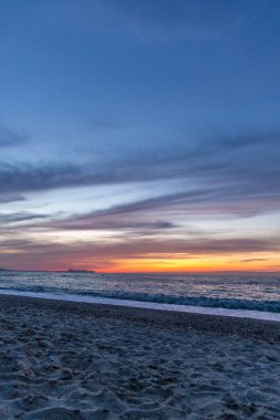 Gün batımında kumlu ve çakıl taşı plajı olan güzel bir sahil şeridi. Platanes Beach, Rethymno, Girit, Yunanistan 'ın turizm ve otel bölgesinde güzel gökyüzü renklendirmesi