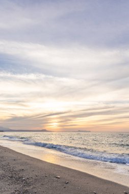Gün batımında kumlu ve çakıl taşı plajı olan güzel bir sahil şeridi. Platanes Beach, Rethymno, Girit, Yunanistan 'ın turizm ve otel bölgesinde güzel gökyüzü renklendirmesi