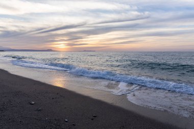 Gün batımında kumlu ve çakıl taşı plajı olan güzel bir sahil şeridi. Platanes Beach, Rethymno, Girit, Yunanistan 'ın turizm ve otel bölgesinde güzel gökyüzü renklendirmesi