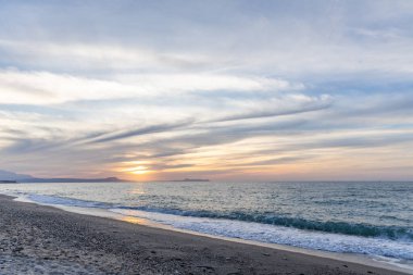 Gün batımında kumlu ve çakıl taşı plajı olan güzel bir sahil şeridi. Platanes Beach, Rethymno, Girit, Yunanistan 'ın turizm ve otel bölgesinde güzel gökyüzü renklendirmesi