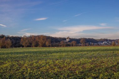 Gün doğumunda çekilmiş bir kış manzarası. Bir sürü doğa ve kayanın üzerinde büyük bir kilise var. St. Lubentius Limburger eski kolej kilisesi, Dietkirchen, Hesse