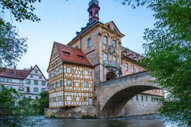 Nehir kenarındaki bir kasabanın manzara fotoğrafı. Köprüdeki tarihi bir binanın görüntüsü. Sabahları yarı keresteli ev ve belediye binası. Bamberg, Bavyera, Almanya 'da Doğa