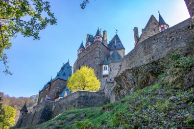 Vadideki kale yeşil bir kayın ormanıyla çevrili. Sabah güneş doğarken çekilmiş. Eltz Nehri üzerinde güzel manzara fotoğrafı, Eltz Şatosu, Almanya