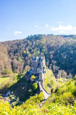 Vadideki kale yeşil bir kayın ormanıyla çevrili. Sabah güneş doğarken çekilmiş. Eltz Nehri üzerinde güzel manzara fotoğrafı, Eltz Şatosu, Almanya