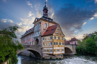 Nehir kenarındaki bir kasabanın manzara fotoğrafı. Köprüdeki tarihi bir binanın görüntüsü. Sabahları yarı keresteli ev ve belediye binası. Bamberg, Bavyera, Almanya 'da Doğa