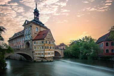 Bamberg 'deki Radhaus Köprüsü. Nehirdeki bir köprü adasında inşa edilmiş. Almanya 'nın tarihi Bavyera şehrinde gün doğumunda şehir manzarası