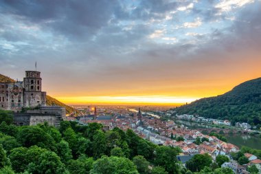 Kale harabeleri olan eski bir kasabanın tepesinden manzara. Almanya, Heidelberg 'de gün batımında manzara