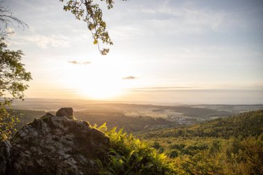 Taunus, Almanya 'da Feldberg' de güzel bir günbatımı. Doğada harika bir manzarayla ön planda bir taş ve yeşillik fotoğrafı çekildi.