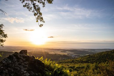 Taunus, Almanya 'da Feldberg' de güzel bir günbatımı. Doğada harika bir manzarayla ön planda bir taş ve yeşillik fotoğrafı çekildi.