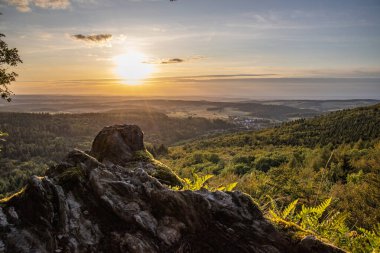 Taunus, Almanya 'da Feldberg' de güzel bir günbatımı. Doğada harika bir manzarayla ön planda bir taş ve yeşillik fotoğrafı çekildi.