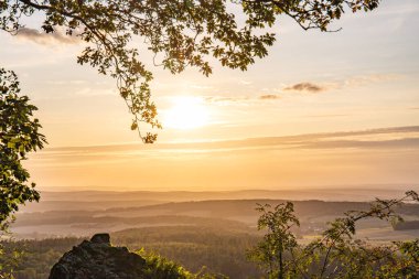 Taunus, Almanya 'da Feldberg' de güzel bir günbatımı. Doğada harika bir manzarayla ön planda bir taş ve yeşillik fotoğrafı çekildi.
