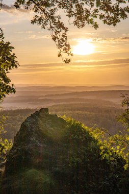 Taunus, Almanya 'da Feldberg' de güzel bir günbatımı. Doğada harika bir manzarayla ön planda bir taş ve yeşillik fotoğrafı çekildi.