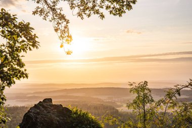 Taunus, Almanya 'da Feldberg' de güzel bir günbatımı. Doğada harika bir manzarayla ön planda bir taş ve yeşillik fotoğrafı çekildi.