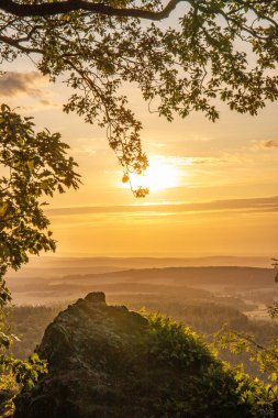 Taunus, Almanya 'da Feldberg' de güzel bir günbatımı. Doğada harika bir manzarayla ön planda bir taş ve yeşillik fotoğrafı çekildi.