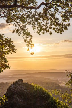 Taunus, Almanya 'da Feldberg' de güzel bir günbatımı. Doğada harika bir manzarayla ön planda bir taş ve yeşillik fotoğrafı çekildi.