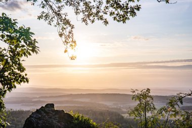 Taunus, Almanya 'da Feldberg' de güzel bir günbatımı. Doğada harika bir manzarayla ön planda bir taş ve yeşillik fotoğrafı çekildi.
