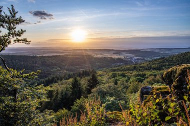 Taunus, Almanya 'da Feldberg' de güzel bir günbatımı. Doğada harika bir manzarayla ön planda bir taş ve yeşillik fotoğrafı çekildi.