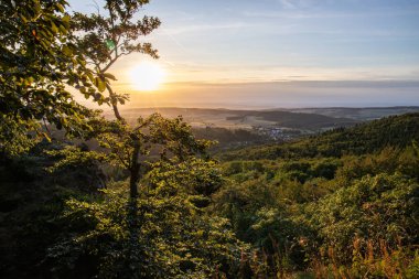 Taunus, Almanya 'da Feldberg' de güzel bir günbatımı. Doğada harika bir manzarayla ön planda bir taş ve yeşillik fotoğrafı çekildi.