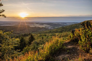 Taunus, Almanya 'da Feldberg' de güzel bir günbatımı. Doğada harika bir manzarayla ön planda bir taş ve yeşillik fotoğrafı çekildi.