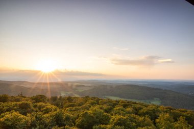 Taunus, Almanya 'da Feldberg' de güzel bir günbatımı. Doğada harika bir manzarayla ön planda bir taş ve yeşillik fotoğrafı çekildi.