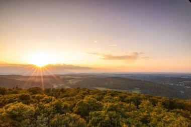 Taunus, Almanya 'da Feldberg' de güzel bir günbatımı. Doğada harika bir manzarayla ön planda bir taş ve yeşillik fotoğrafı çekildi.
