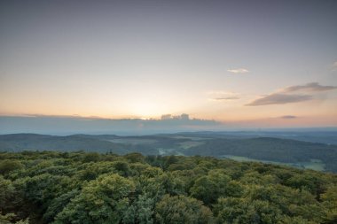 Taunus, Almanya 'da Feldberg' de güzel bir günbatımı. Doğada harika bir manzarayla ön planda bir taş ve yeşillik fotoğrafı çekildi.