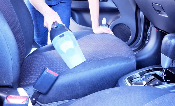 Woman cleaning car seats with vacuum cleaner.