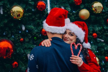 Noel aşkı. Noel Baba şapkalı adam ve kadın Noel ağacının yanında. 