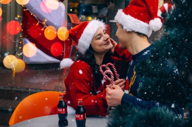 Noel aşkı. Noel Baba şapkalı bir adam ve kadın Noel ağacının yanında. Kafede aşk