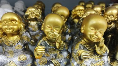 Golden statues of a boy who does not hear, does not see and touches his face with his hands. High quality photo
