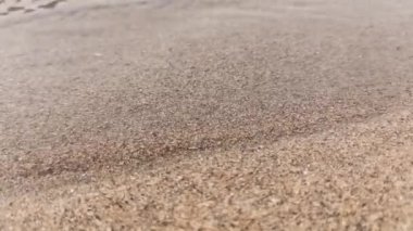 A small stream flows through the sand on the beach by the ocean at sunset. High quality FullHD footage