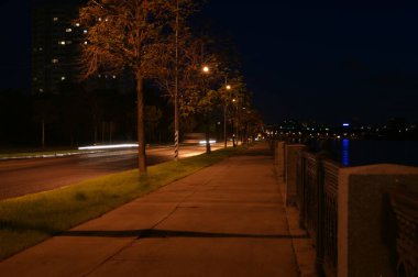 city lighting poles off the road, evening landscape. Night in the city. Sidewalk near the river.