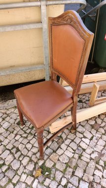Portekiz 'in Lizbon bölgesinde eski bir deri döşemeli sandalye bir çöp tenekesinin yanında duruyor. Yüksek kalite fotoğraf
