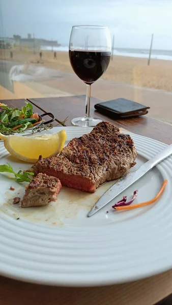 Delicious steak with salad and red wine in an oceanfront restaurant. High quality photo