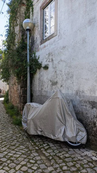在葡萄牙里斯本辛特拉的一条人行横道上 摩托车站在一面旧墙下 上面覆盖着一种特殊的布 斗篷和摩托车设备 — 图库照片