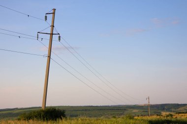 Yüksek voltajlı uzun beton çubuk hafifçe eğimli ve düzgün durmuyor, hattın onarılması gerekiyor. Alanda onarılması gereken bir elektrik hattı var.