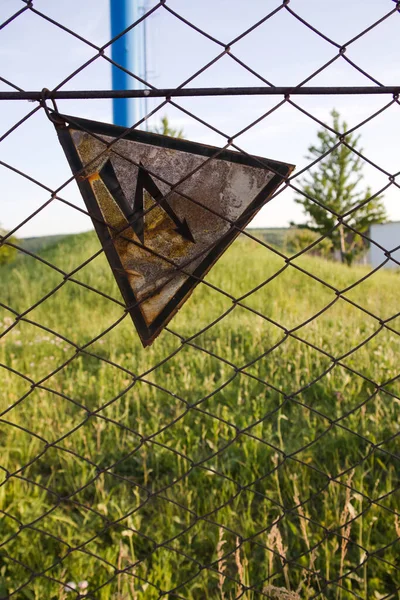 On the old fence, a sign hangs from a metal mesh that warns passers-by about the danger - the fence is energized and a person risks being electrocuted